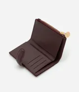 Billetera tipo sobre de Satinato, confeccionada en material sintético efecto gamuza color bordó. Presenta un cierre principal con tirador metálico circular grabado y una solapa central con textura tipo reptil.