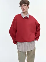 Buzo oversize de corte amplio y relajado, color rojo, con cuello redondo acanalado, mangas anchas y bajo regulable mediante elásticos.