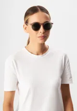 Lentes de sol redondos con montura gris translúcido y lentes verdes. Fabricados con acetato biodegradable y lentes de PMMA reciclado.