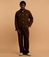 Campera trucker marrón, de corte overboxy y manga larga, confeccionada en sarga de algodón. Tiene cuello inglés, cierre abotonado, bolsillos con solapa y pespunte contrastante.