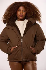 Campera reversible para mujer con diseño acolchado de nylon en un lado y corderito sintético en el otro. Cuenta con capucha, cierre frontal y mangas largas.