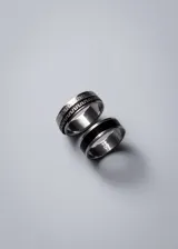 Anillo de acero quirúrgico color plateado con banda giratoria y diseño de guarda griega en negro.