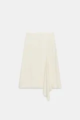 Falda midi de tiro medio, color blanco off-white, confeccionada en hilatura de viscosa. Presenta un diseño fluido, con bajo asimétrico y detalle de caída drapeada en el lateral. Cierre con cremallera oculta en costura.