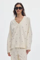 Buzo de felpa sin frisa color marfil con estampado de lunares negros, escote en V y diseño holgado.