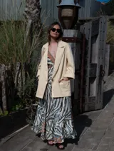 Blazer color crema de corte recto, con cuello de solapa, mangas largas y bolsillos laterales.