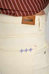 Pantalón de jean color beige, de corte wide leg con botamanga desflecada y tiro medio, diseñado especialmente para maternidad.