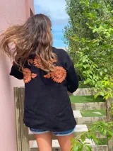 Cárdigan negro de lana merino con bordados de flores color naranja.