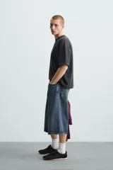 Camiseta gris de corte cuadrado y holgado, con cuello redondo y mangas cortas.