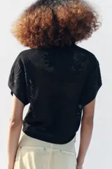 Top de punto pointelle color negro, con cuello redondo y mangas cortas anchas de diseño holgado.