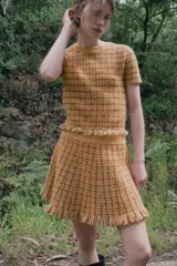 Falda mini de tiro medio confeccionada en tejido de punto con diseño de cuadros y acabado en flecos en el ruedo. Cuenta con cintura elástica.