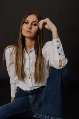 Camisa blanca de voile de algodón con bordado floral, corte clásico, cuello camisero y cierre frontal con botones. Mangas largas con puños abotonados.