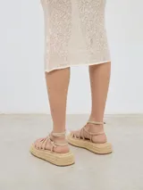 Sandalia con plataforma de esparto, tiras delanteras a diferentes niveles y cierre con hebilla al tobillo.