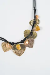 Collar de doble cordón negro con dijes colgantes en forma de corazón con texturas variadas y cuentas de piedra en tonos amarillos y dorados.