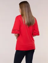 Remera blanca de silueta recta y algodón suave, con escote redondo y pequeña abertura central tipo gota. Presenta mangas de largo intermedio con aplicación horizontal de puntilla calada al tono y ruedo recto con tajos laterales.
