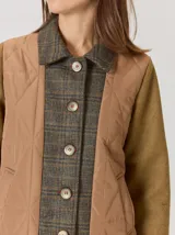 Campera de diseño híbrido con frente acolchado en color tostado, solapas y cuello en tejido de lana con patrón de cuadros tipo príncipe de gales, y mangas en paño de lana color azul marino. Cuenta con cierre frontal de botones.