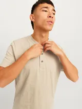 Remera básica de manga corta en color beige, con cuello mao y cartera corta con botones. Confeccionada en jersey de algodón.