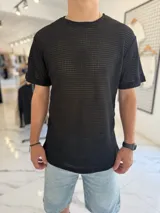Remera negra de corte oversize y manga corta, confeccionada en tejido de punto con trama abierta y efecto texturizado.