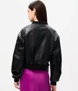 Campera bomber de cuero sintético negro, con cierre frontal de cremallera, cuello alto y puños y bajo elásticos con rib. Presenta costuras decorativas en los hombros.
