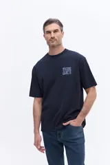 Remera de manga corta color azul marino con cuello redondo y calce regular. Presenta un estampado artístico en la espalda con diseño floral estilizado y tipografía.