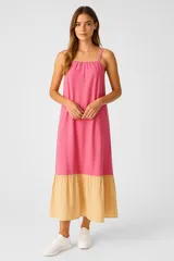 Vestido largo de lino, color block en fucsia y beige, con tirantes finos, cuello cuadrado, corte holgado y bolsillos.
