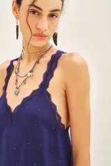 Top negro de viscosa con breteles finos y escote en V con puntilla. Presenta apliques de tachas termo adhesivas en el frente.