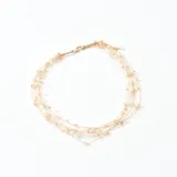 Collar corto de múltiples hilos dorados con pequeñas cuentas color durazno.