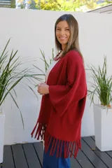 Saco abierto tipo capa en color bordó, confeccionado en tejido de punto suave, con mangas amplias y detalle de flecos en el ruedo.