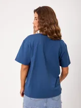 Remera de algodón marca Rusty, color blanco, de corte holgado, con cuello redondo, mangas cortas y estampado frontal colorido de temática tropical.