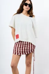 Minifalda de rayas verticales en tonos bordó y beige, confeccionada en tejido elástico con fruncidos laterales regulables mediante cordones.