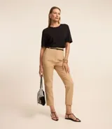 Pantalón de sastrería corte carrot, color beige, con cintura alta, pinzas delanteras y cinturón fino incluido con hebilla metálica. Presenta un diseño estructurado con ajuste holgado en la cadera y pierna ligeramente estrecha.