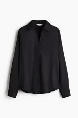 Blusa negra de tela satinada con brillo, cuello clásico, escote en V con botones frontales, mangas largas con puños sencillos y bajo redondeado.