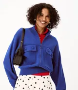 Campera de punto pesado color azul, con cuello alto, cierre frontal con cremallera y bolsillos delanteros con solapa y botones. Cuenta con mangas largas y puños y bajo acanalados.