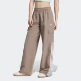 Pantalón cargo Adidas color marrón con corte holgado, cintura elástica con cordón ajustable, bolsillos laterales y bolsillos cargo. Presenta las tres rayas blancas características de la marca en los laterales.