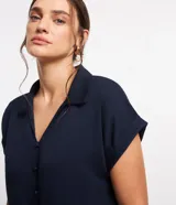 Blusa azul marino de viscosa con cuello solapa, abotonado delantero, mangas cortas con doblez y lazo en la parte baja.