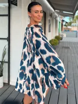 Blusa de satén con estampado animal print en tonos azul, beige y marrón. Presenta un corte holgado, cuello redondo y mangas largas tipo globo con volumen.