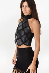 Top halter negro confeccionado con una mezcla de cuero y tejido artesanal, con diseño geométrico de rombos unidos por costuras de crochet y dobladillo en punta.