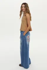 Jean wide leg azul de tiro medio, confeccionado en algodón, con pinzas en el frente y detalle de bordado debajo del bolsillo trasero.