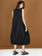 Vestido midi negro de popelina con corte globo y detalle de flor en el hombro.