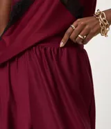 Pantalón de corte aladino con volumen en las piernas, confeccionado en tejido piquet. Presenta cintura elástica y detalle de lazos para anudar en los tobillos.