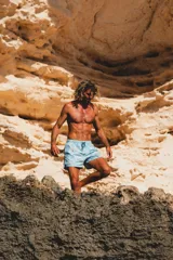 Short de baño color celeste con estampado botánico de hojas y flores en tonos verdes, naranjas y violetas. Cuenta con cintura elástica, bolsillos laterales y un bolsillo trasero con etiqueta de la marca.