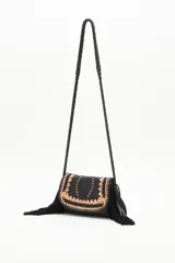 Cartera bandolera negra de cuero con diseño trenzado y apliques dorados en el frente, flecos de cuero en la parte inferior y correa trenzada.