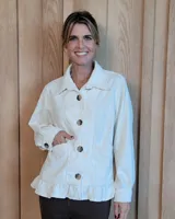 Sobrecamisa de pana color crudo, con cuello clásico, cierre frontal de botones, bolsillos delanteros y detalle de volado en el ruedo.