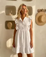 Vestido corto blanco de lino, con cuello mao, cierre frontal con botones de nácar, volados en las sisas y falda con volado en el ruedo.