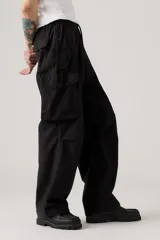 Pantalón cargo negro de corte holgado, con cintura elástica y cordón ajustable. Presenta bolsillos laterales y bolsillos cargo con solapa en los muslos.