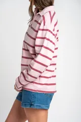 Sweater tipo polo de manga larga con diseño a rayas horizontales en tonos rosado y bordó. Presenta cuello camisero con solapa y cierre frontal parcial.