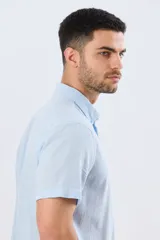 Camisa de manga corta confeccionada en mezcla de lino y algodón, color beige, con cuello camisero abotonado, bolsillo frontal en el pecho y cierre de botones.