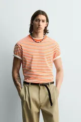 Camiseta de corte regular fit confeccionada en tejido de algodón, con diseño de rayas horizontales en color naranja y blanco, cuello redondo y manga corta.