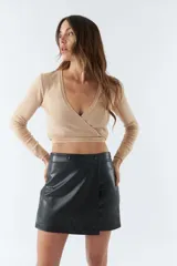 Top tejido de punto con diseño cruzado, escote en V y mangas largas. Cuenta con tiras para anudar en la cintura y detalle de grifa de cuero.