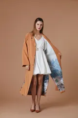 Saco Natalia Antolin de mujer color verde oscuro, de corte largo y diseño relajado con cuello redondo, mangas anchas y cierre frontal de botones oscuros. Incluye una etiqueta decorativa distintiva de la marca en el puño de la manga izquierda.