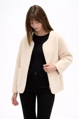 Chaqueta de pana color natural, con cuello a la base, cierre frontal y bolsillos delanteros tipo parche. Diseño holgado de manga larga.